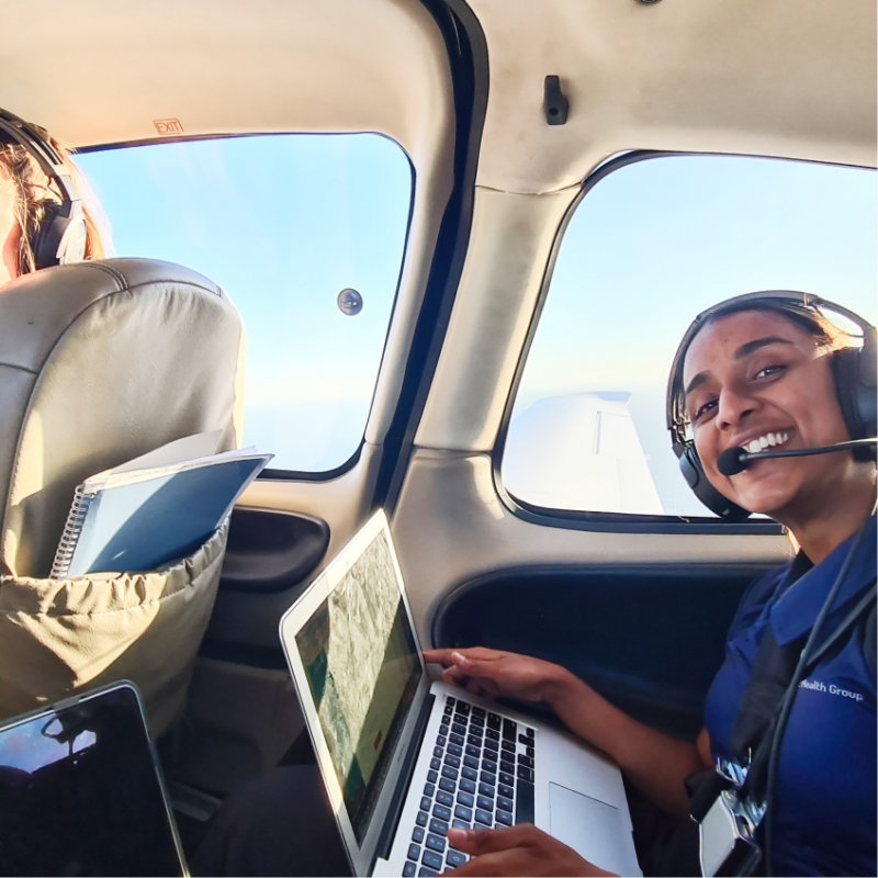 A flying doctor smiles while on her laptop mid-flight