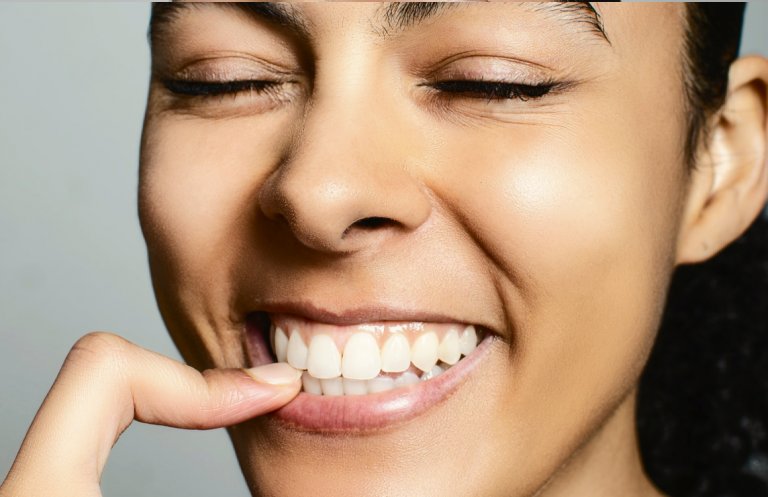 A woman shows her set of healthy teeth
