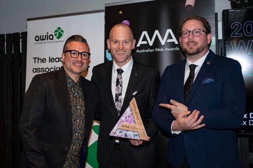 A representative from the Australian Web Awards stands next to Dux Digital's Managing Director, Justin Greenwood, and General Manager, Barry Marelli, as they receive their award trophy